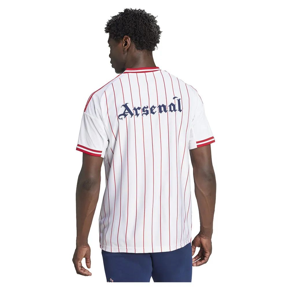 7938842c-d767-41f4-95bb-01095424b5f5 | UAE SPORT STORE Back view of a man wearing a white football jersey with red vertical pinstripes and 'Arsenal' text on the back, red-trimmed sleeves, paired with navy shorts.