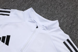 White zip-front athletic jacket with black three-stripe sleeves on a gray carpeted surface.