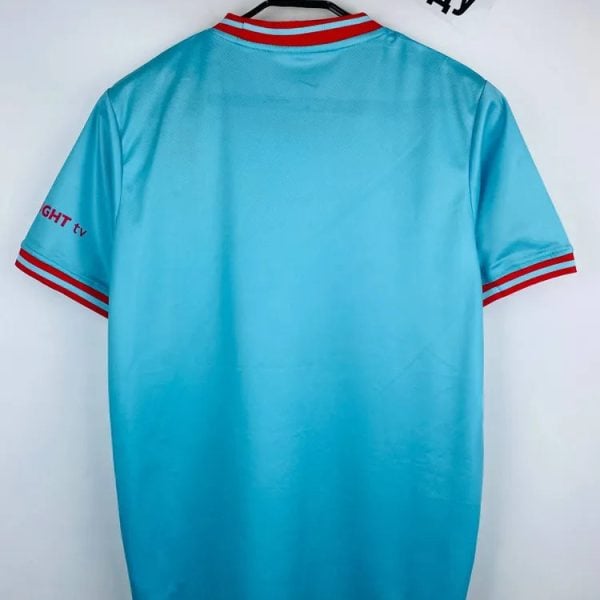 Light blue sports jersey on a hanger with red and white striped collar and sleeve cuffs on both arms.