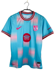 FC Barcelona jersey on a hanger: light blue with pink gradient, with Nike swoosh, Barça crest, and Spotify sponsor logo.
