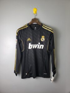 Real Madrid goalkeeper jersey hanging on a brown hanger with gold accents and the club crest visible on the chest.