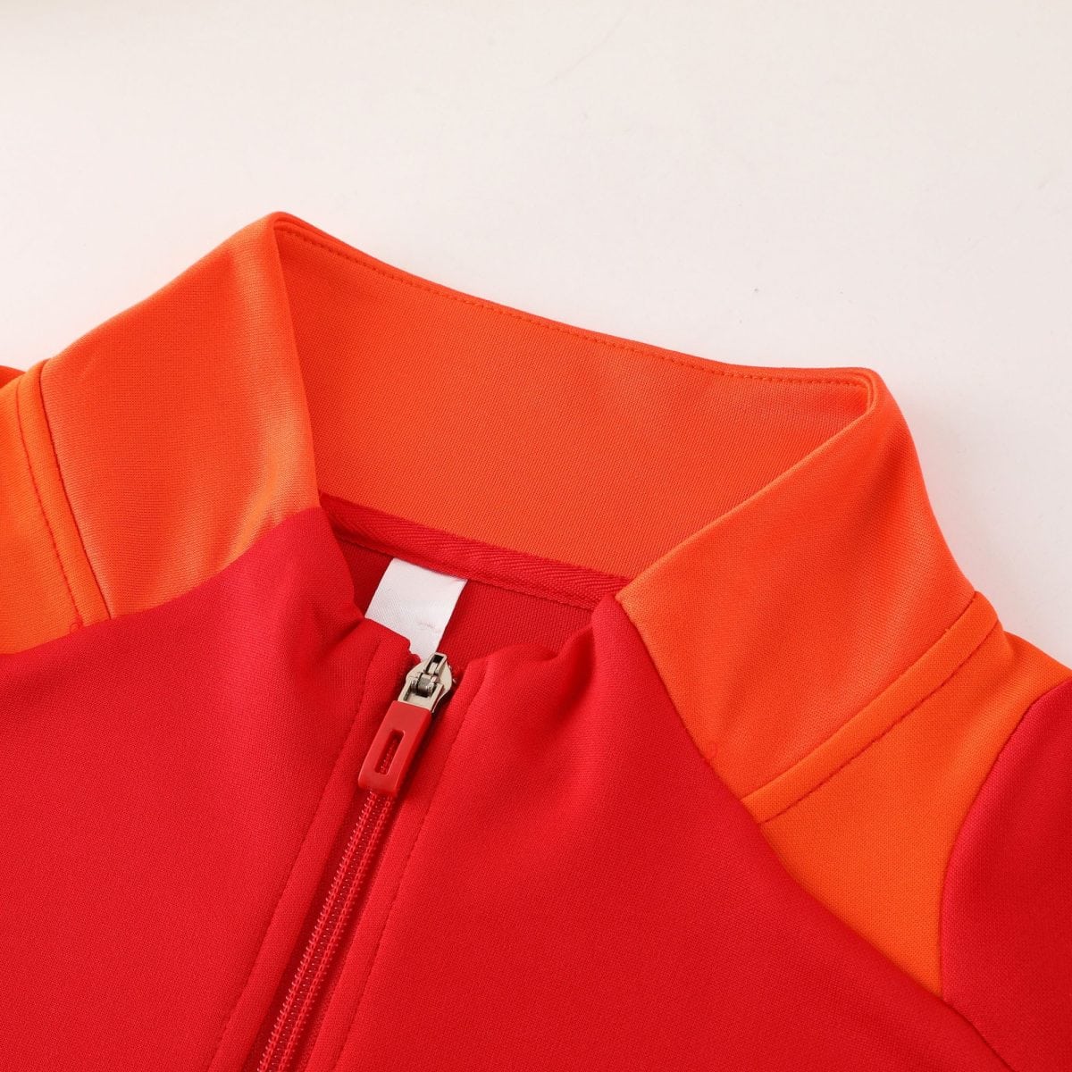 Close-up of bright orange fabric with a metal zipper and orange zipper pull.