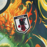 Close-up of a flame-themed sports jersey featuring the Japan Football Association (JFA) patch with a black eagle and red ball emblem.