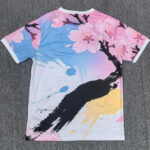 Back view of a pastel floral T-shirt with pink cherry blossoms, light blue and white background, and bold black brushstroke design.