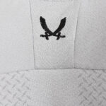 Close-up of light gray fabric with black embroidery depicting two crossed swords forming a V shape, on upholstery.