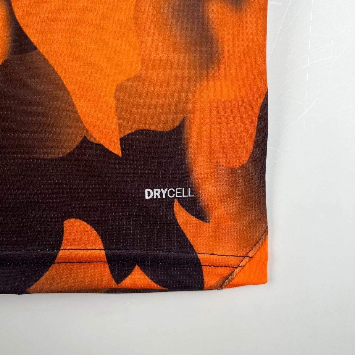 Close-up of orange and black patterned fabric with visible stitching and the word DRYCELL.