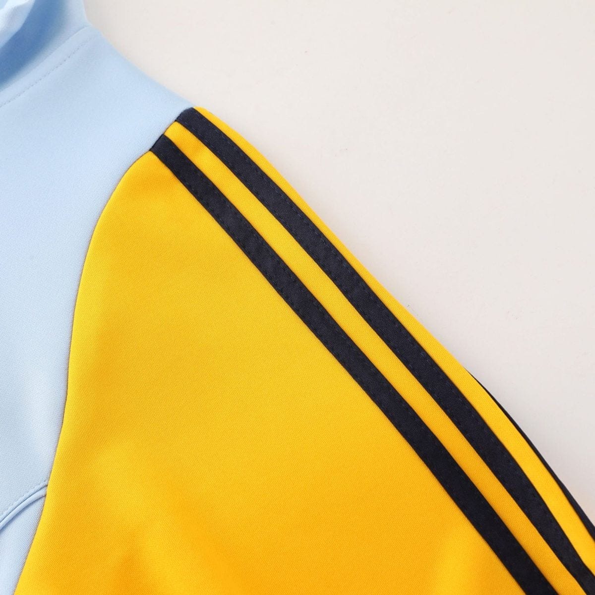Close-up of light blue fabric beside a yellow fabric with two dark navy stripes in the corner transition.