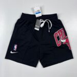 Black basketball shorts with a white drawstring, NBA logo patch near the hem, and a large red graphic on the right leg with a Nike swoosh nearby on the left.