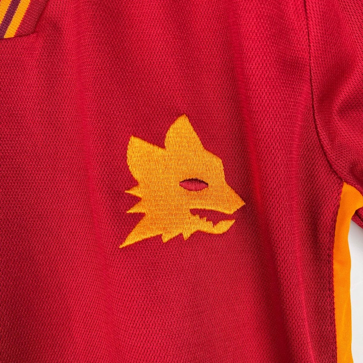 Close-up of red knitted fabric with an orange maple leaf graphic.