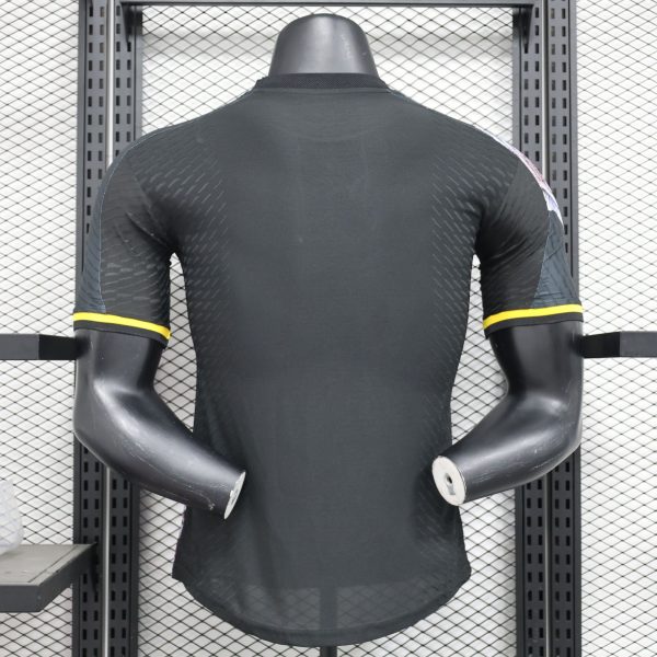 Mannequin torso wearing a black athletic shirt with yellow sleeve trim, displayed on a metal rack with a grid background.