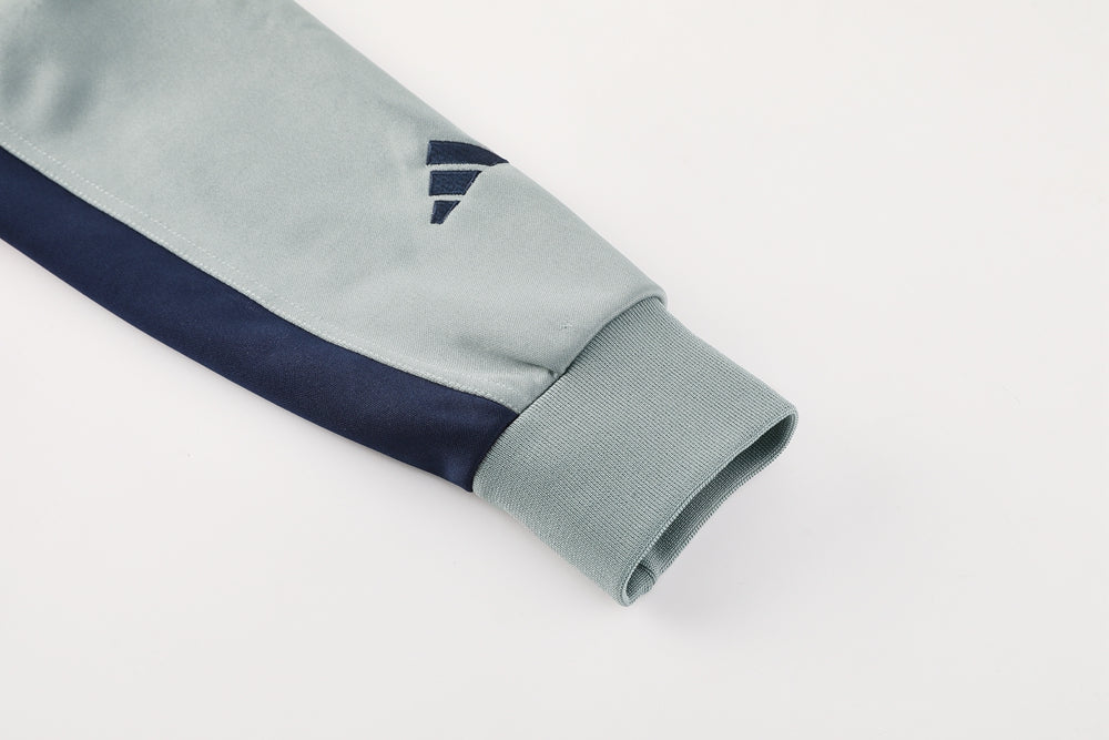 7b1f3f70 | UAE SPORT STORE Close-up of a light gray jacket sleeve with a navy stripe near the elbow and a ribbed cuff at the wrist.