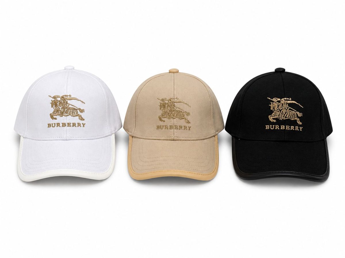 Three Burberry baseball caps in white, tan, and black with gold embroidered equestrian logo and 'BURBERRY' text (front view).