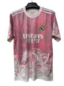 Pink Real Madrid football jersey on a hanger, with the Emirates Fly Better sponsor and club crest visible.
