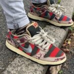 Multi-color Nike sneakers with red stripes and camouflage patches resting on a concrete step.
