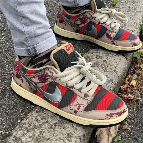 Multi-color Nike sneakers with red stripes and camouflage patches resting on a concrete step.