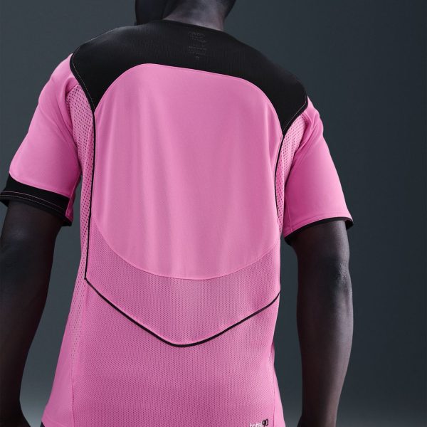 Back view of a person wearing a pink athletic jersey with a black shoulder yoke and mesh panels, logo near the hip