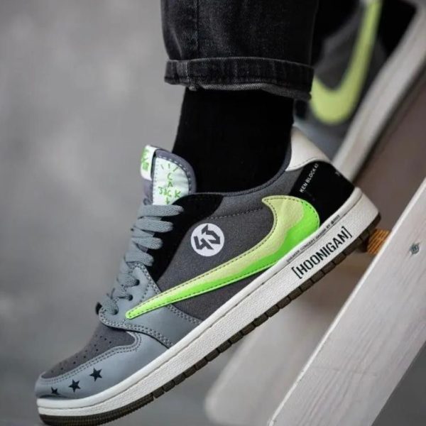 Grey and black sneakers with neon green swoosh worn with rolled jeans, resting on a white step.