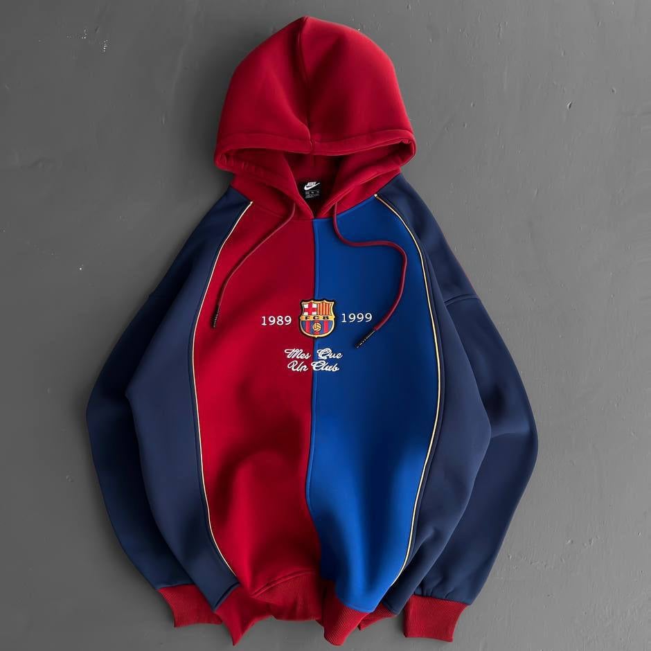 7c60c96f-7271-477c-a13c-7011d01d8277 Red and blue color-block hoodie with FC Barcelona crest and the years 1989–1999.