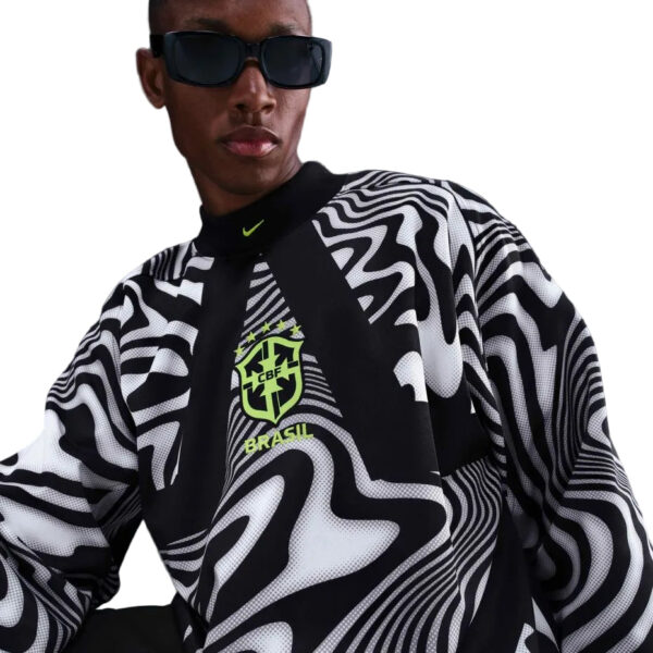Person wearing a black-and-white swirling-pattern sports jersey with a Brazil crest and neon-green accents, sunglasses on.