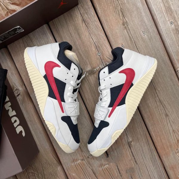 Pair of white, navy, and red Nike sneakers on a wooden deck beside a brown shoebox.
