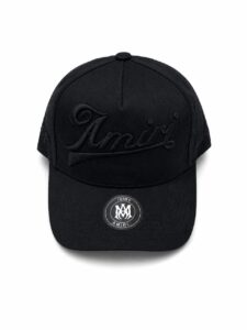 Black baseball cap with black-on-black 'Amiri' embroidery and a circular brand sticker on the brim, shown from the front.