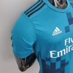 7e83efec_f55092a7-119d-4103-95b8-bbedfdb10900 | UAE SPORT STORE Close-up of a turquoise Adidas jersey shoulder showing the black three-stripe design and part of the Adidas logo on the chest.