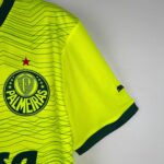 Close-up of a neon yellow sports jersey showing a circular crest with stars and green trim on the sleeve edge.