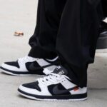 Close-up of black and white Nike sneakers on a concrete sidewalk with laces tied.
