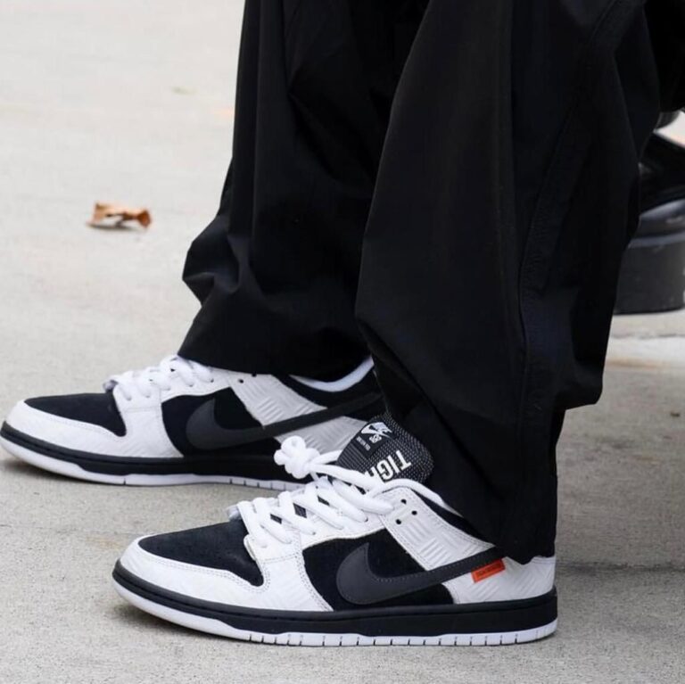 Close-up of black and white Nike sneakers on a concrete sidewalk with laces tied.