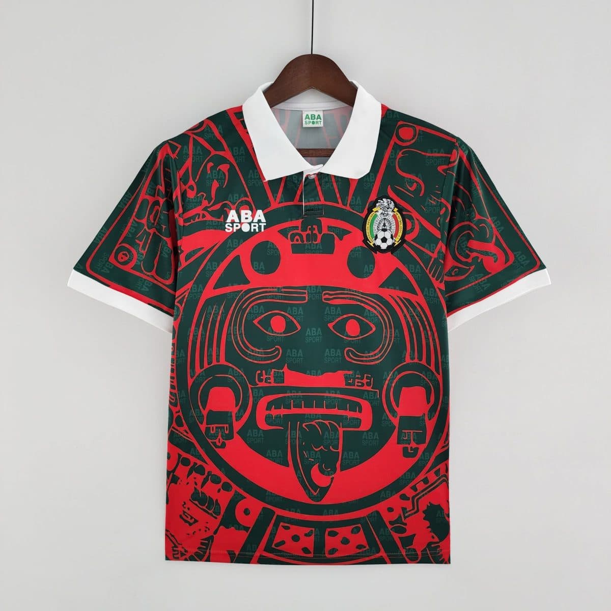 Dark green and red patterned sports jersey on a wooden hanger with a white collar; ABA SPORT branding visible on the chest area.