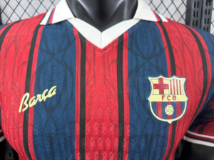 7f6d7588_227e5947-58ca-44a6-99a6-7498cc827180 | UAE SPORT STORE Close-up of a Barcelona FC jersey showing red and blue vertical stripes, white collar, and the Barça signature with the FCB crest on the chest.