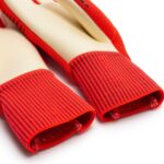Close-up of bright red ribbed fabric cuffs from long gloves, showing stitching at the ends.