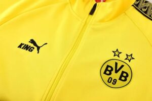 Close-up of a bright yellow Borussia Dortmund jacket showing the Puma King logo and the BVB 09 crest with two stars above it.