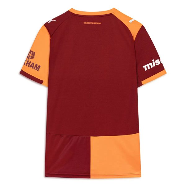 Back view of a color-blocked maroon and orange sports jersey with orange shoulder panels and sleeves, featuring white brand logos on the shoulders and sponsor text near the neckline.