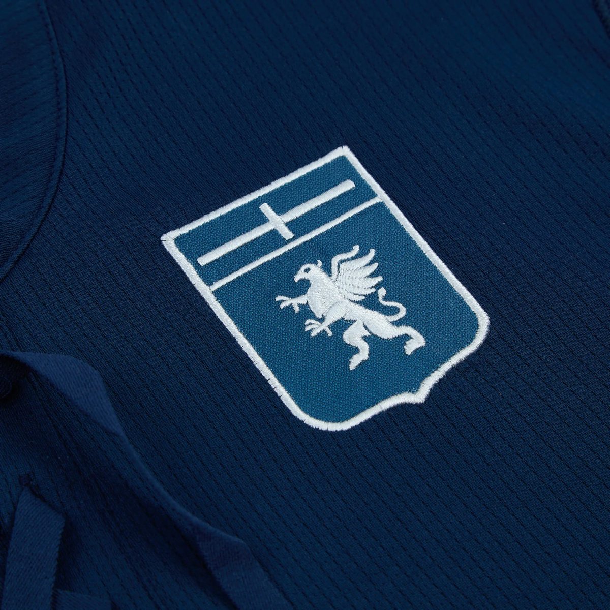 Close-up of navy fabric with an embroidered patch: a blue shield featuring a white eagle outlined in white border.