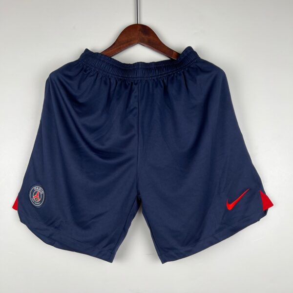 Navy athletic shorts on a hanger with PSG badge on the left leg and a red Nike swoosh on the right leg.