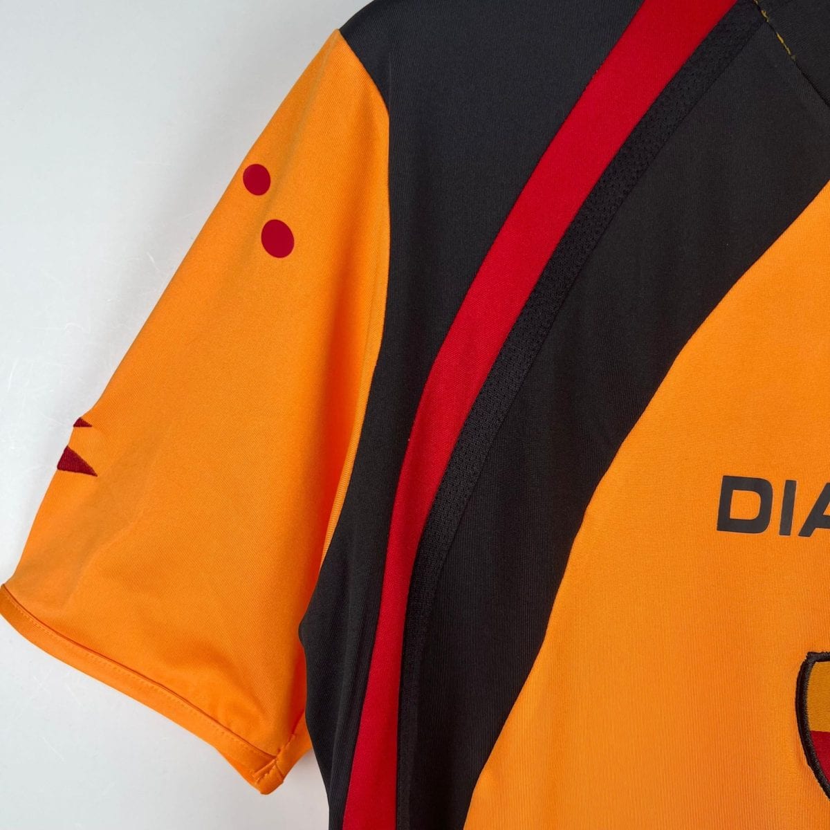 Close-up of an orange high-visibility vest with red diagonal stripe and black fabric panels.