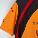 Close-up of an orange high-visibility vest with red diagonal stripe and black fabric panels.