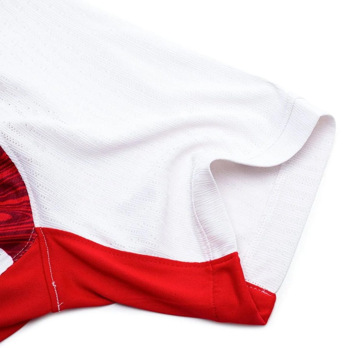 Close-up of white textured fabric with a red seam or trim visible in the bottom-left corner.