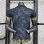 Mannequin from behind wearing a dark graphic T-shirt with gold ornamental cuffs and hem, in a gym rack setting
