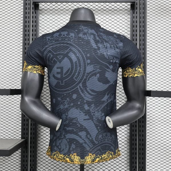 Mannequin from behind wearing a dark graphic T-shirt with gold ornamental cuffs and hem, in a gym rack setting