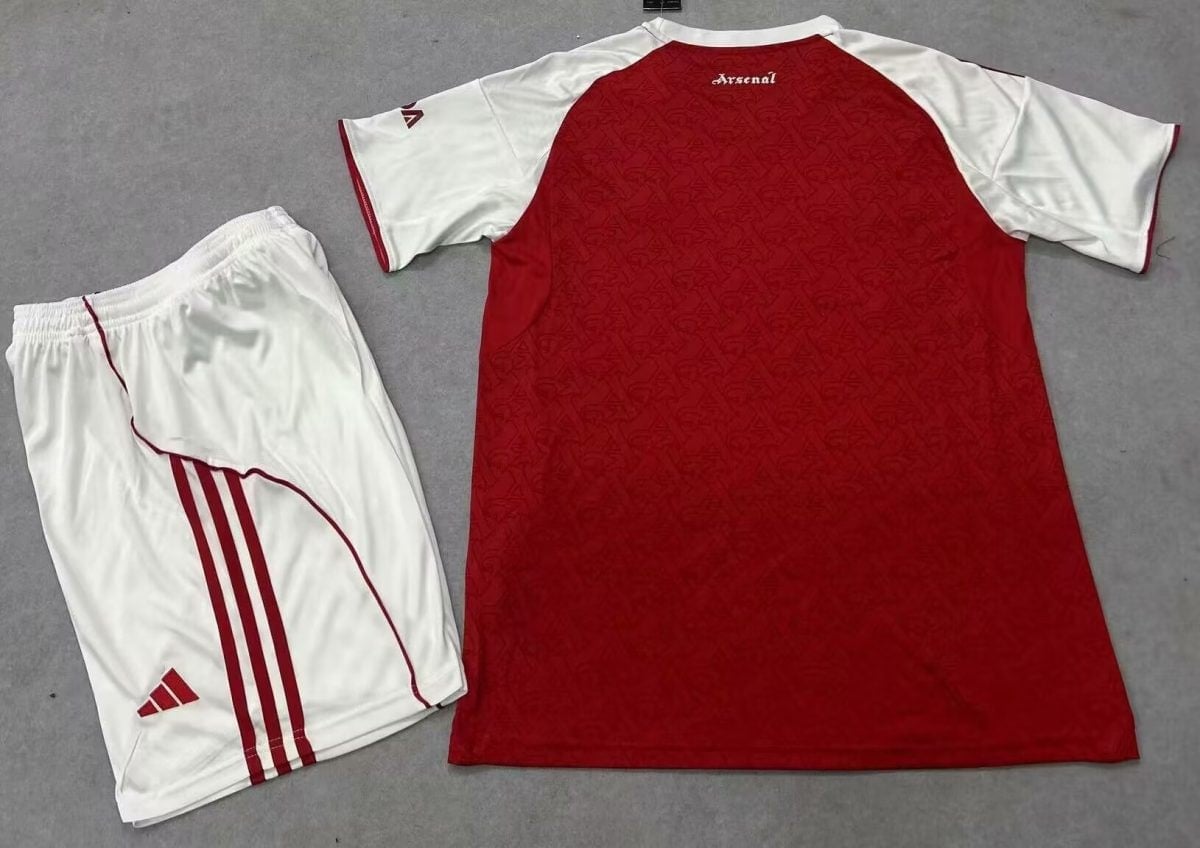 Arsenal football kit laid flat: red short-sleeve jersey with white sleeves and 'Arsenal' near the neck; white shorts with red Adidas stripes.