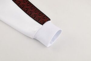 White shirt cuff with a dark red and black patterned trim along the sleeve edge.