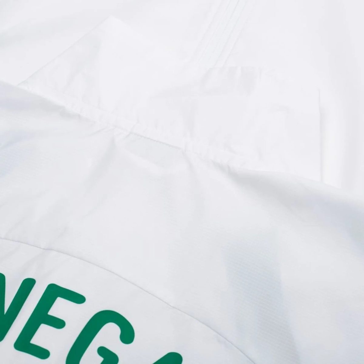 Close-up of a white pillow with a curved seam and partial green text along the edge, suggesting a printed design.