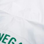 Close-up of a white pillow with a curved seam and partial green text along the edge, suggesting a printed design.