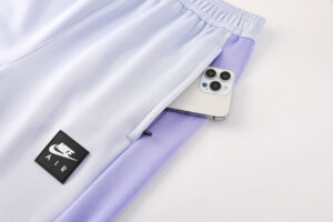 8397515c | UAE SPORT STORE Light lavender-to-white athletic pants with a phone tucked in the side pocket and a Nike Air patch visible on the leg pocket.