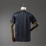 Back view of a navy short-sleeve shirt with geometric panels and gold piping on the cuffs, displayed on a dress form.