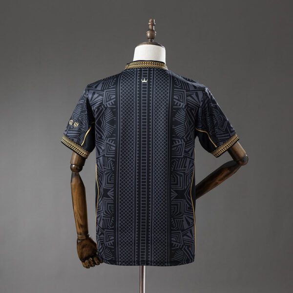 Back view of a navy short-sleeve shirt with geometric panels and gold piping on the cuffs, displayed on a dress form.