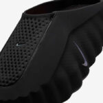 Black athletic gaiter with perforated mesh and small Nike swoosh logos on front and side, close-up view.