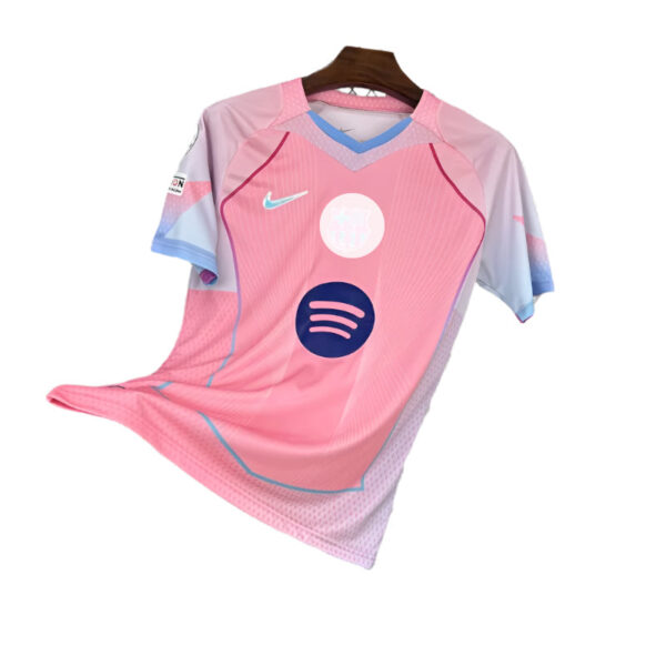 Pink soccer jersey on a hanger with blue sleeves and light accents, featuring Nike swoosh and a Spotify logo on the front.